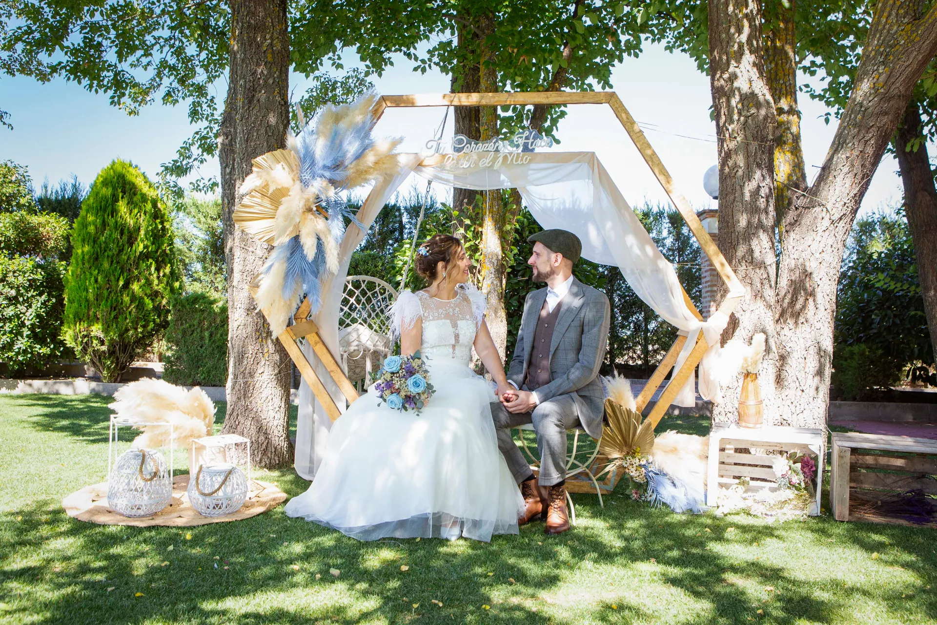 Novios en un photocall boho bajo los árboles de Finca Los Rosales de Cubas
