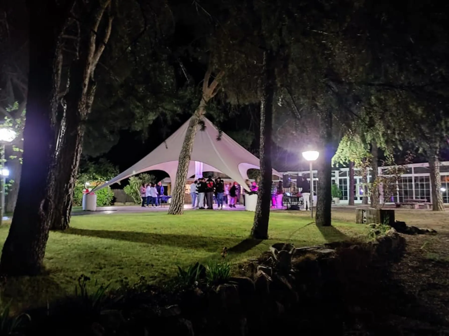 Carpa iluminada entre pinos durante la fiesta en Finca Quinta La Galana