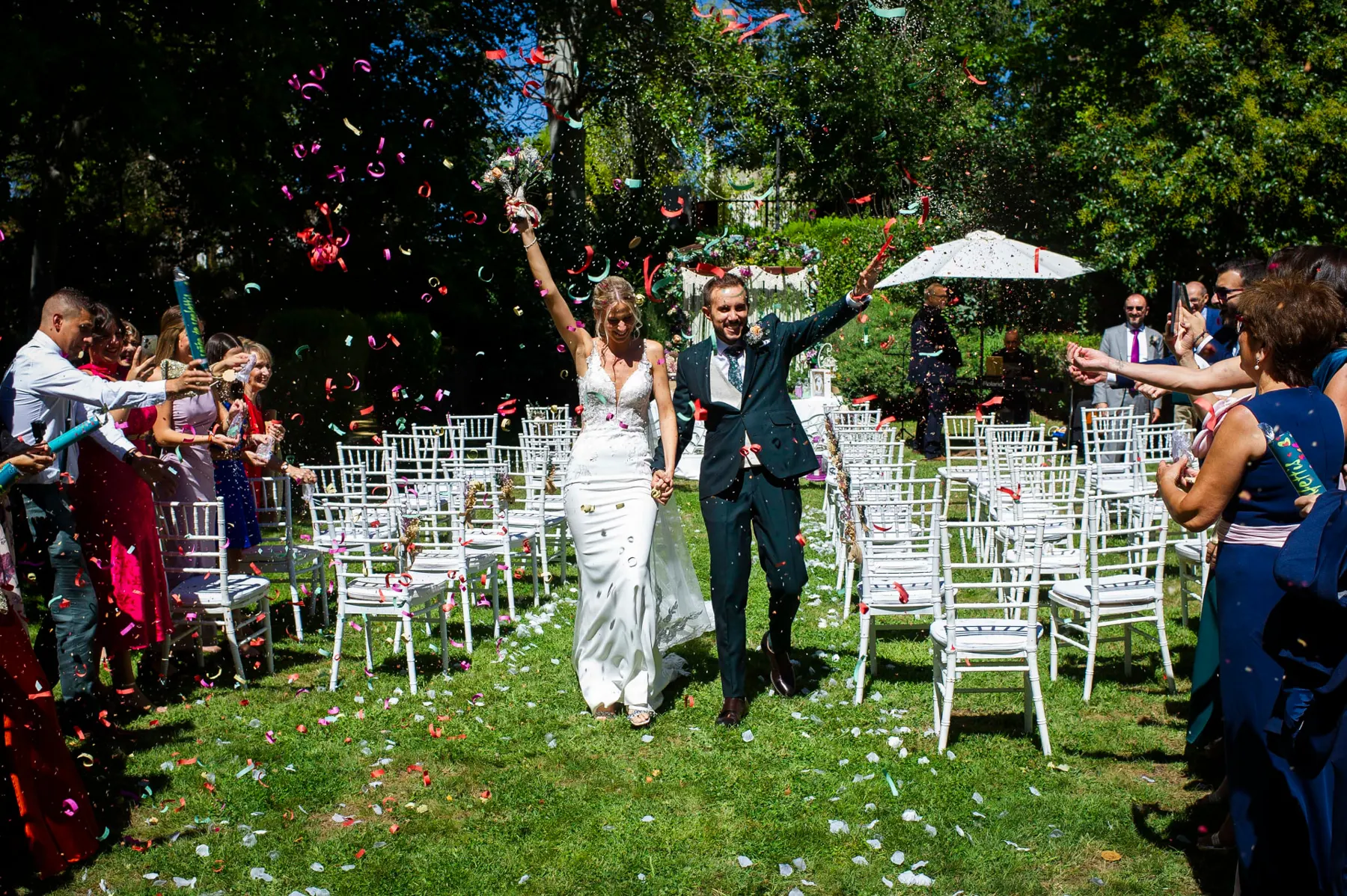 Novios saliendo entre confeti tras la ceremonia en el jardín de Finca La Peraleña