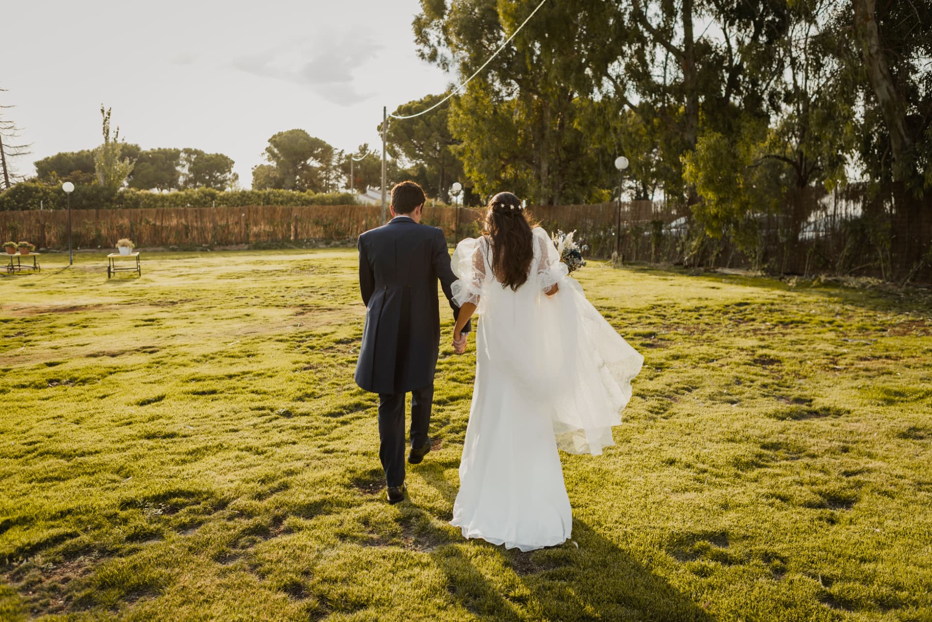 Pareja de recién casados atravesando un prado al atardecer en una finca de Madrid