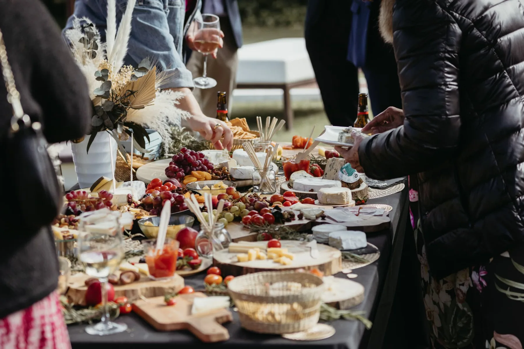 Mesa de quesos y aperitivos con frutas y flores secas en un cóctel al aire libre