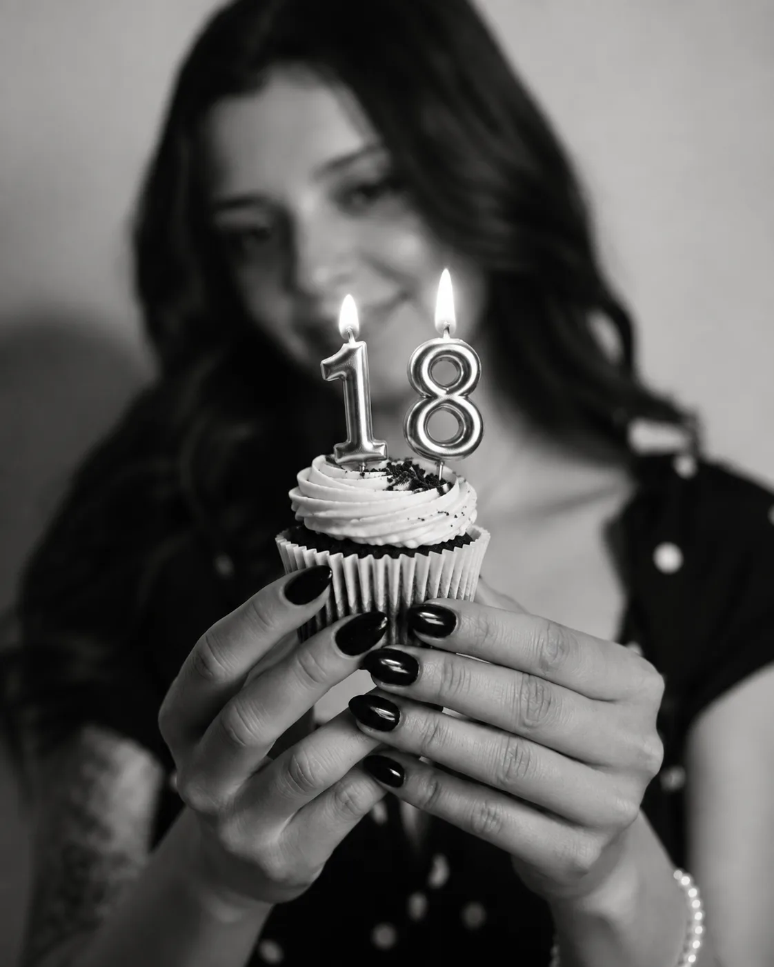 Chica sosteniendo una cupcake con velas de 18 años encendidas