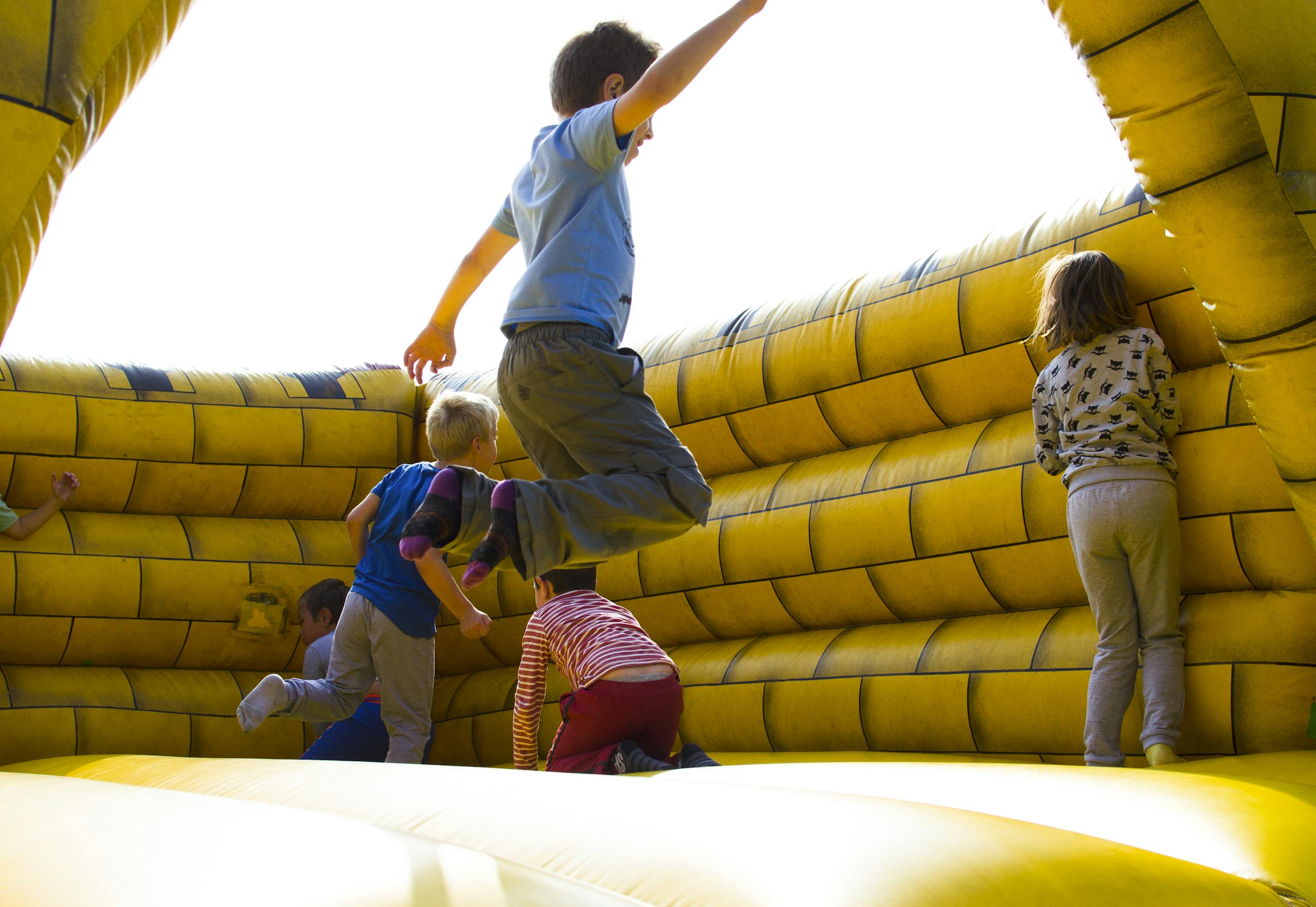 Kids enjoying a fun time bouncing in a vibrant inflatable castle outdoors.